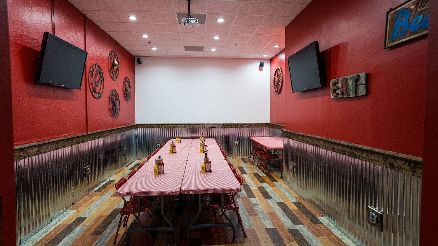 Wing Barn dining room with red folding chairs and a wall-mounted TV