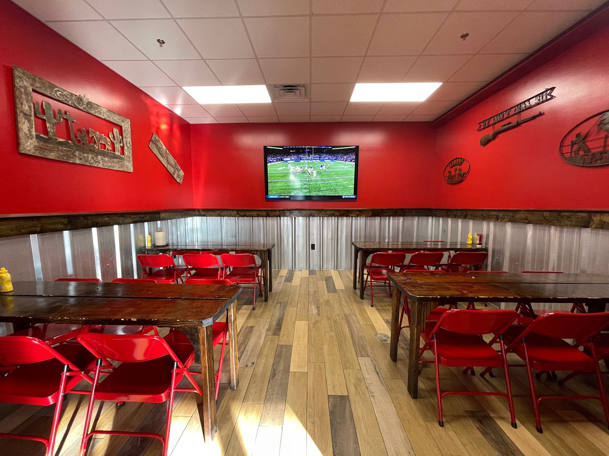 Wing Barn dining room with red walls and a TV showing football